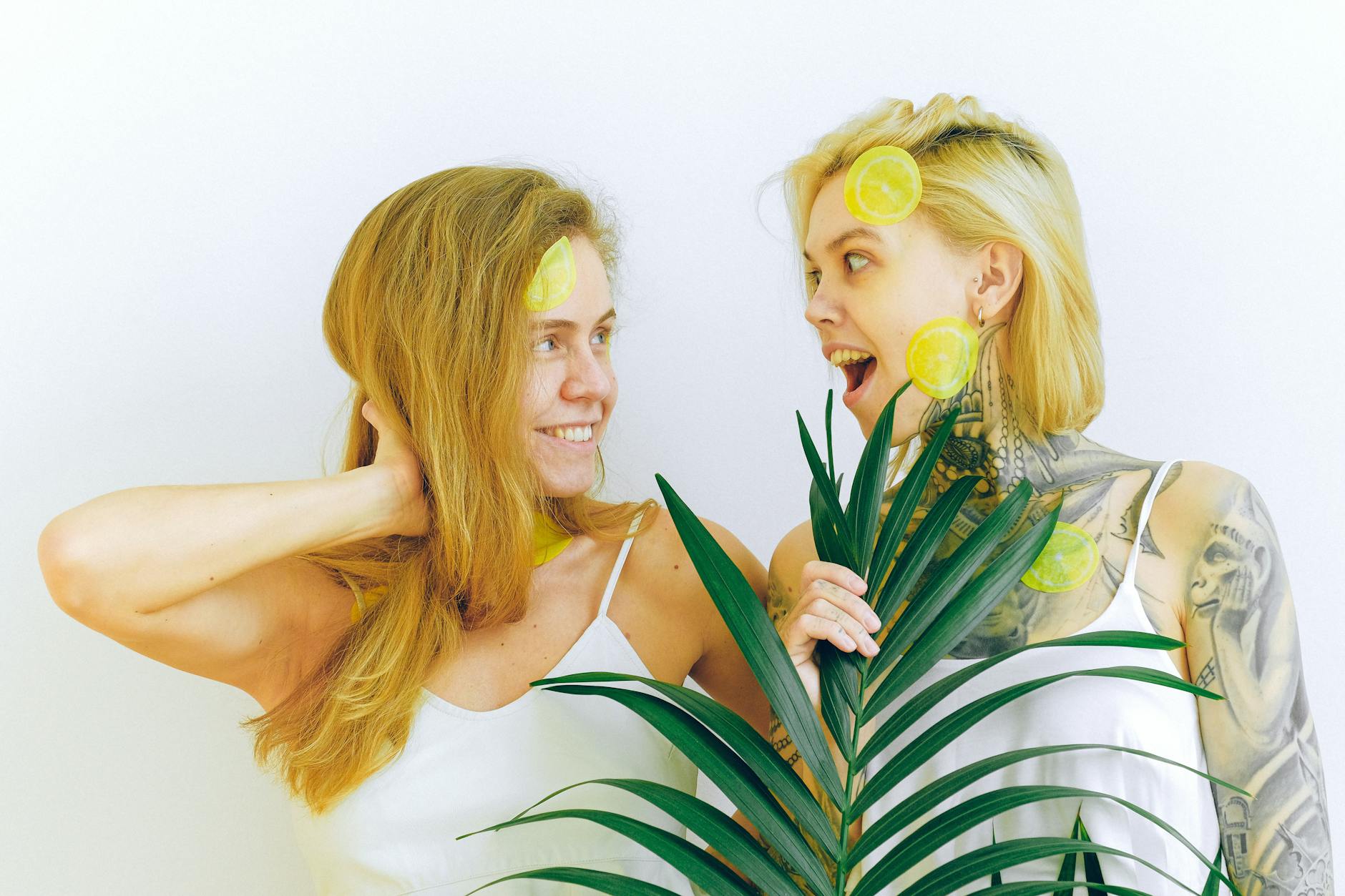 Two women smiling together with lemon slices, expressing joy and confidence