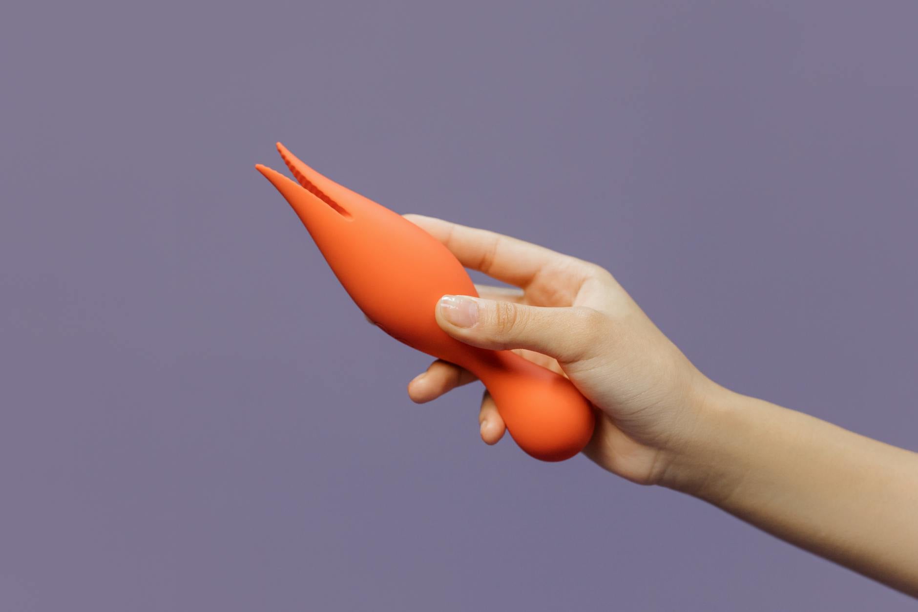 Close-up of hand holding a lemon vibrator against a minimalistic purple background, showcasing modern sensuality.