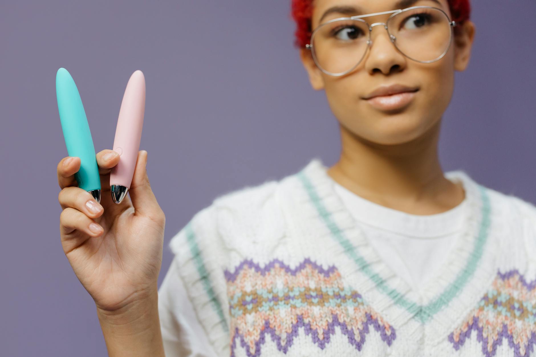 A blue silicone sex toy held in hand against a solid purple background, promoting self-love and sexuality.