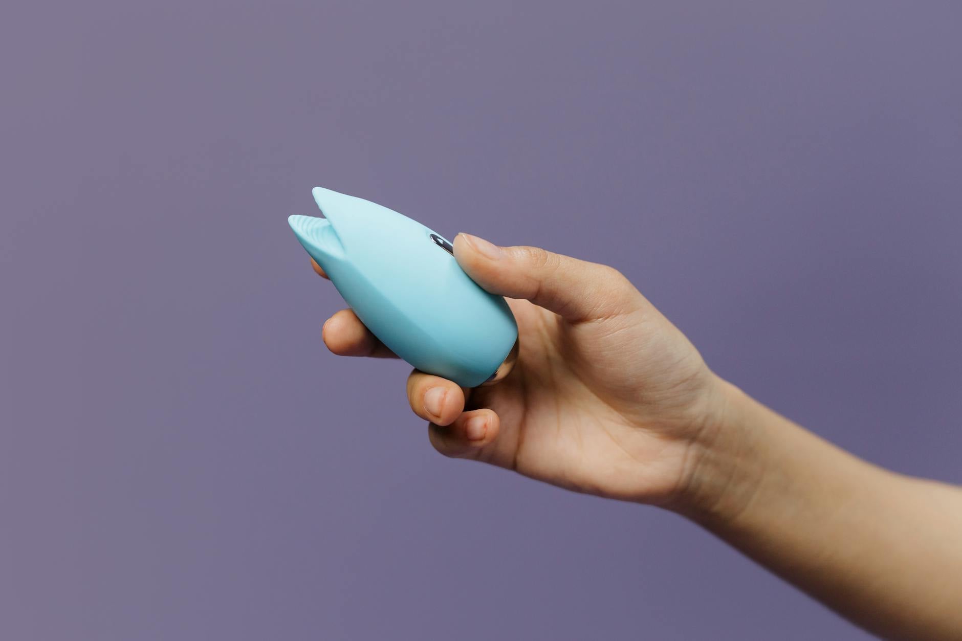 Blue lemon vibrator held in hand against a purple background, promoting self-pleasure and sexual wellness.