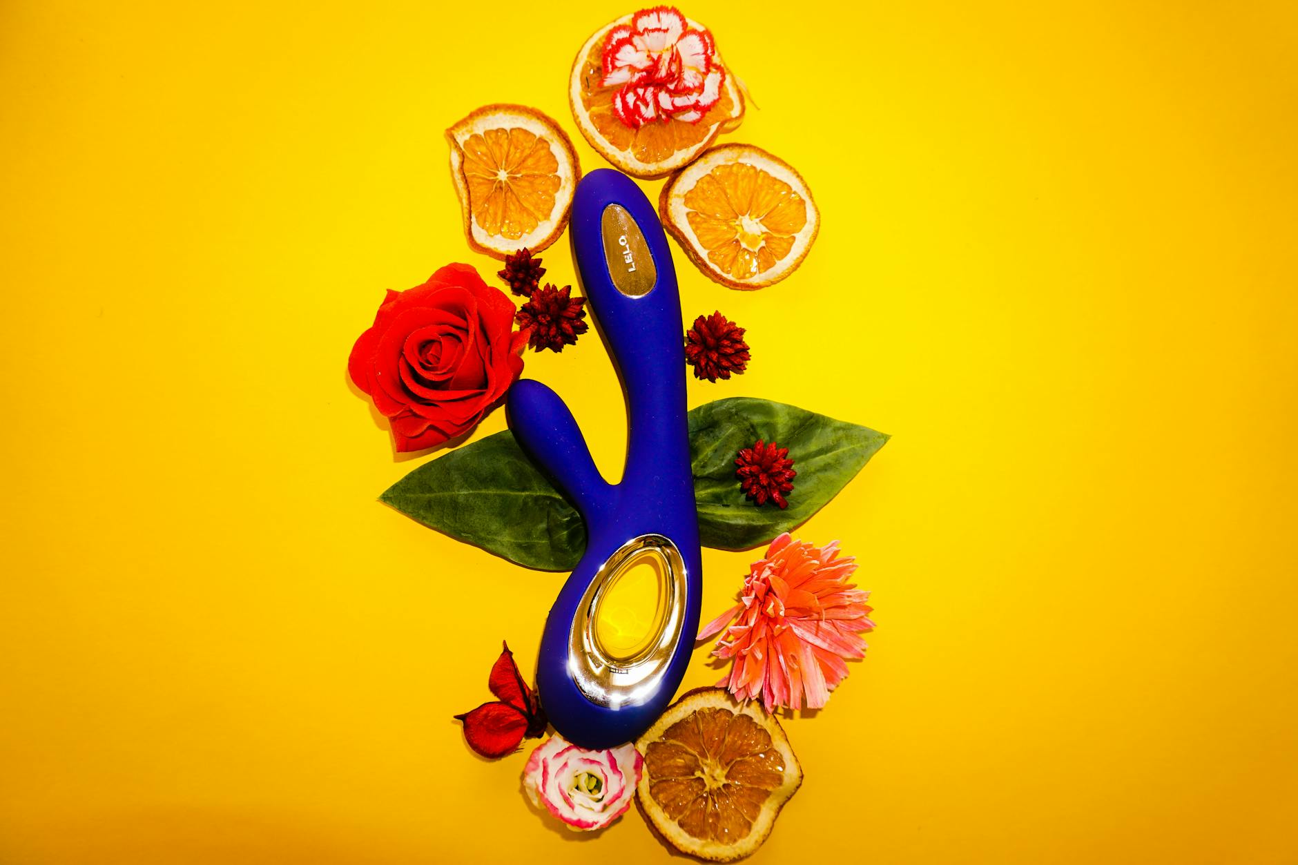 Blue lemon vibrator surrounded by fresh citrus and flowers on bright yellow background