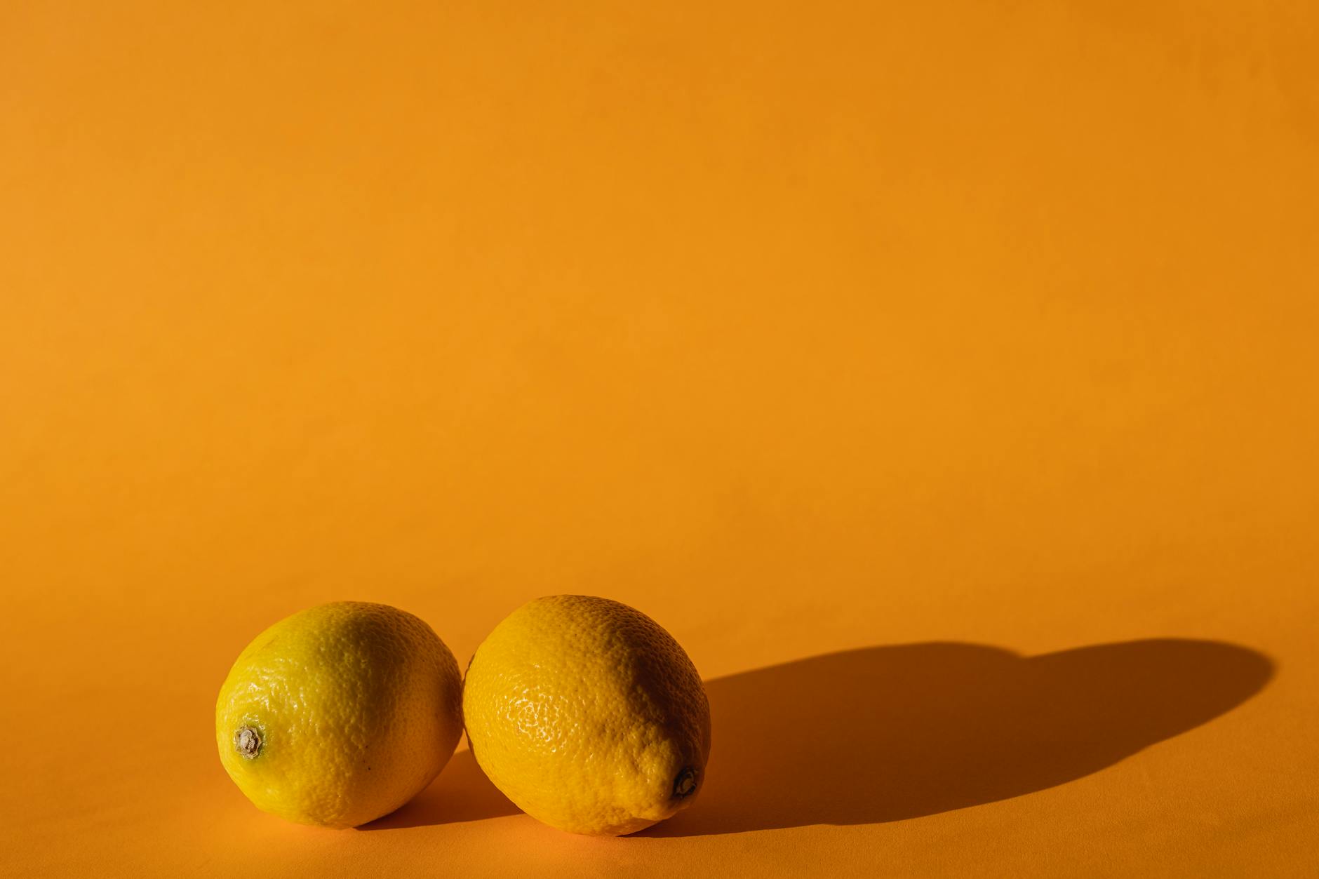 Two fresh lemons held in cupped hands on a brown surface, symbolizing renewal and freshness